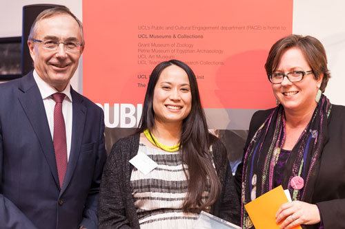 Three people side by side, from left to right a man in glasses and a maroon tie, a shorter woman with long dark brown hair who is pregnant and a taller woman with short brown hair and glasses. They are all smiling