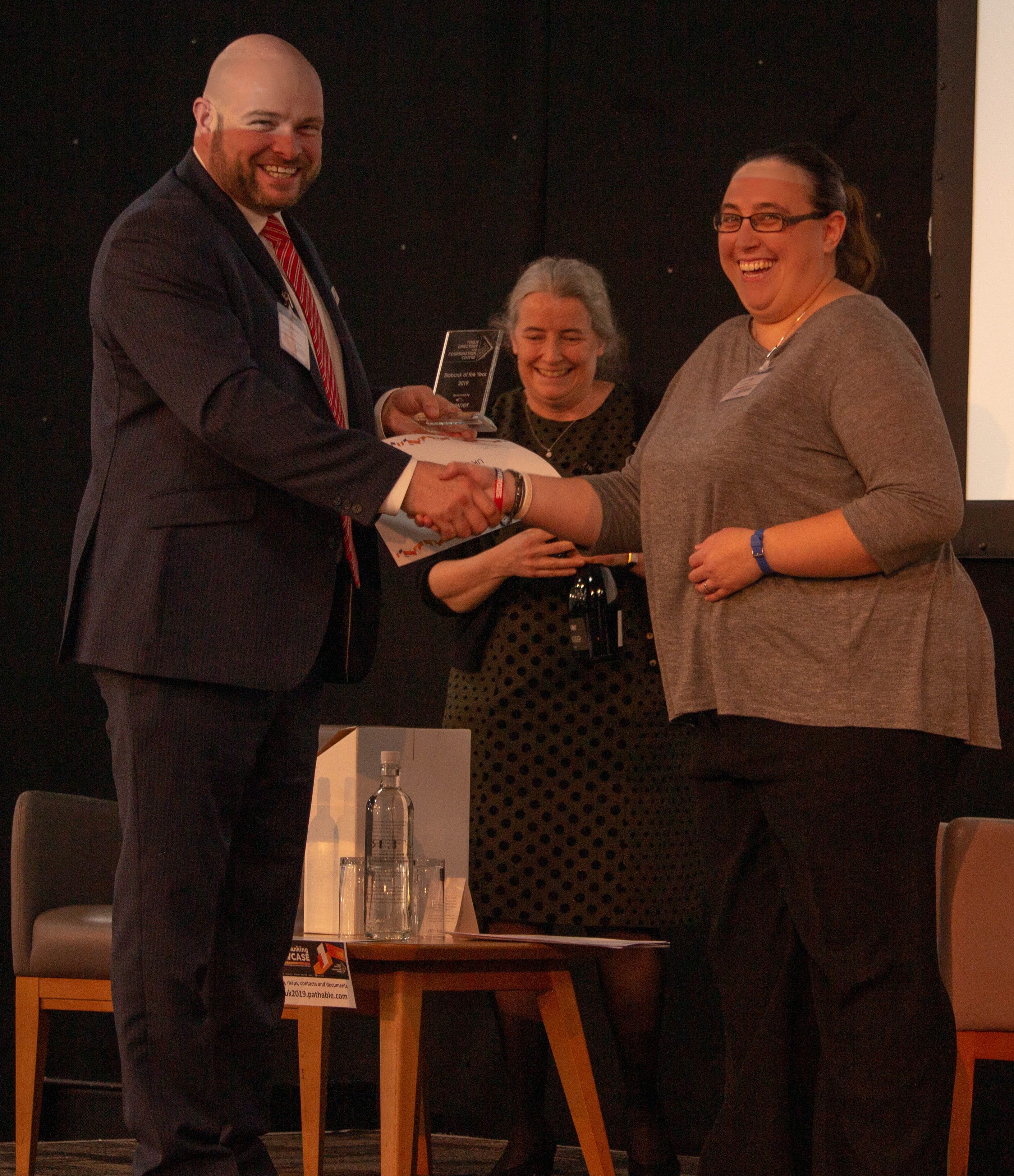 James Siddorns from Greiner Bio-One, award sponsor, congratulating Kirsten Kelly. Amanda Gibbon, Chair of the steering committee, looks on after announcing the winner. 