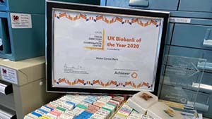 Framed Biobank of the Year Award certificate perched above open drawer of paraffin embedded tissue samples. The clear award trophy is placed to the right of the certificate