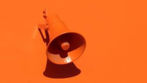 Orange conical speaker mounted on an orange wall